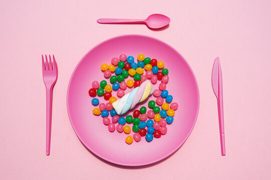 Studio shot of plastic plate full of candies and single marshmallow