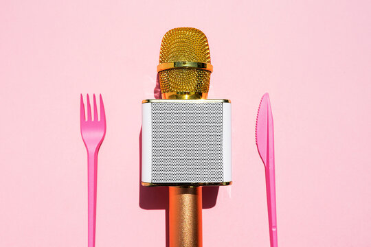 Studio shot of golden microphone and plastic cutlery