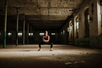 Athlete crouching while exercising at abandoned factory