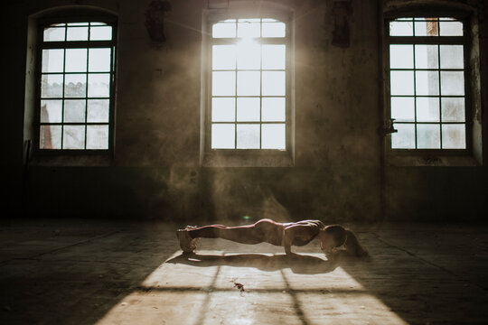 Athlete doing push ups on floor at abandoned factory