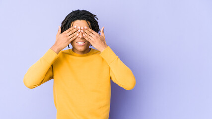 Young black man wearing rasta hairstyle afraid covering eyes with hands.