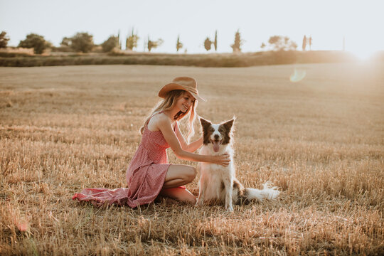 Woman enjoying with border collie dog in wheat field during sunset