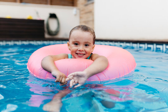 Portrait of little girl with floating tire in pool