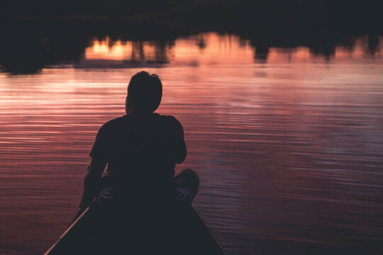 Rear view of man rowing boat in river during sunrise