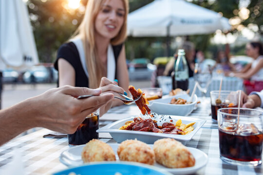 Happy friends having meal while sitting outdoors at cafe