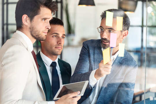 Businessman explaining coworkers over sticky notes during meeting