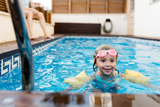 Little girl with swimming goggles in swimming pool