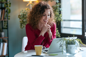 Happy businesswoman using laptop while working from home