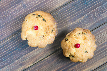 two cupcakes with red berries on a wooden table top view close up