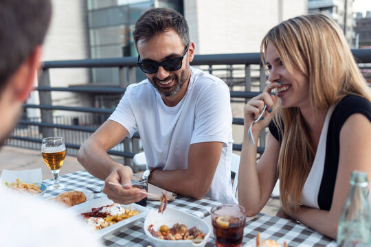 Smiling friends having meal while enjoying at restaurant