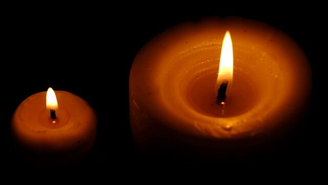 Two stearin candles are burning on a black background high resolution video clip