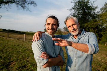 Mature father talking to adult son on a meadow in the countryside