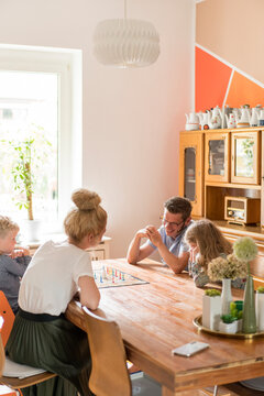 Family playing board game on dining table at home during weekend