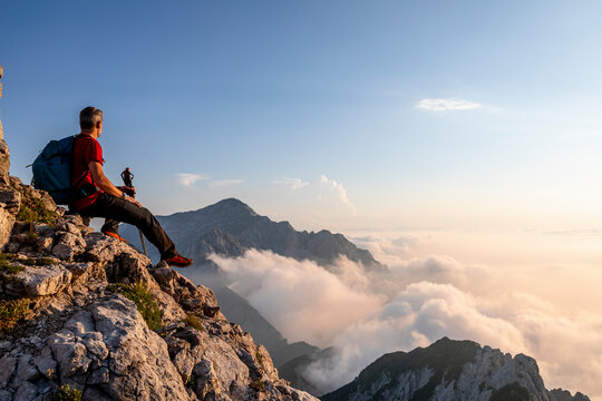 Hiker admiring view while sitting on top of mountain peak at Bergamasque Alps, Italy