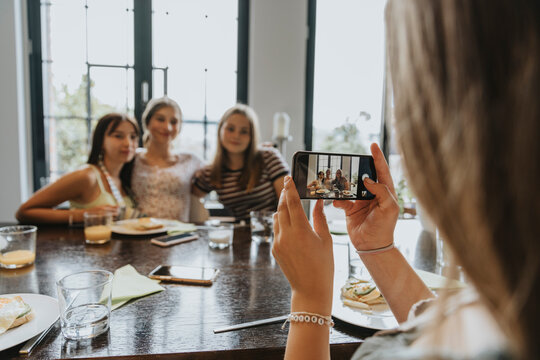 Group of teenage girls meeting for brunch, taking smartphone pictures