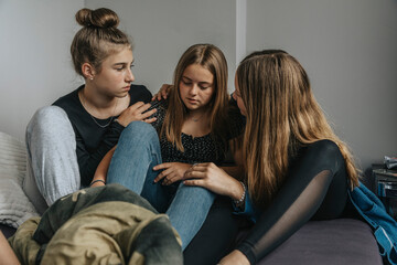 Girlfriends consoling sad teenage girl