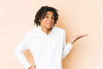 Young african american rasta man doubting and shrugging shoulders in questioning gesture.