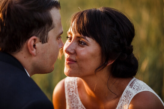 Close-up of bridal couple looking at each other during sunset