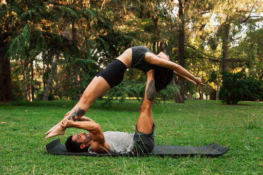 Boyfriend lifting girlfriend while practicing acroyoga in park