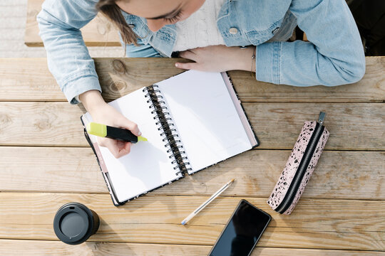 Student with felt tip pen and book at table