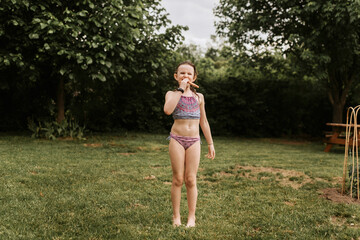 Girl wearing bikini and eating in garden