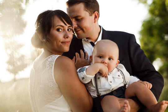 Beautiful young bride with bridegroom and son at wedding during sunset