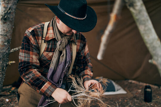 Bushcrafter wearing hat while preparing for campfire