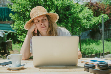 Tired woman relaxing while sitting with laptop at table in back yard