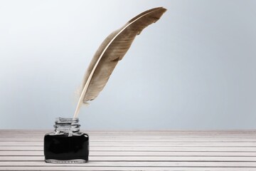 Feather quill pen and glass inkwell