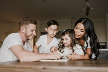 Smiling parents solving jigsaw puzzle with kids on table at home
