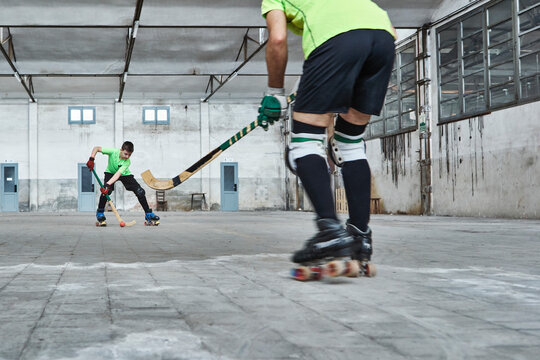 Father and son playing roller hockey on court