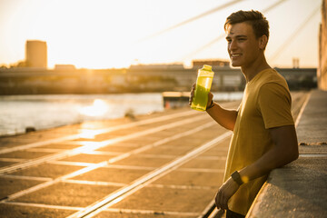 Man with water bottle after workout against clear sky