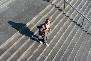 Male professional with bag moving down on staircase in downtown during sunny day