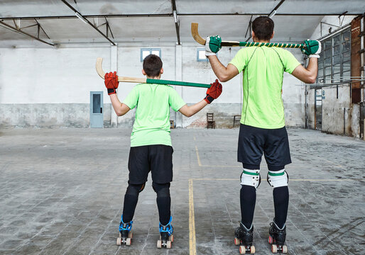 Father and son in sports uniform holding hockey sticks at court