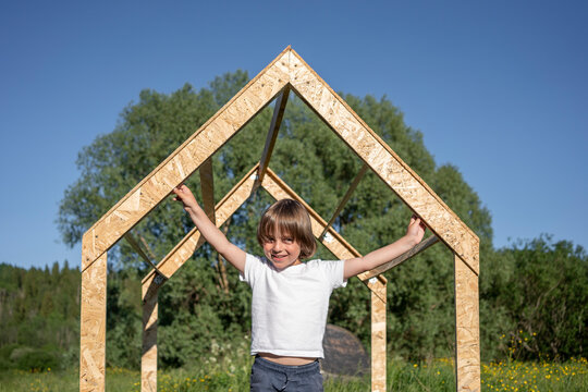Happy boy holding playhouse frame on sunny day