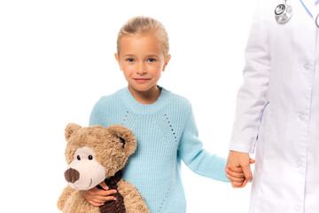 Girl with teddy bear holding hand of pediatrist isolated on white