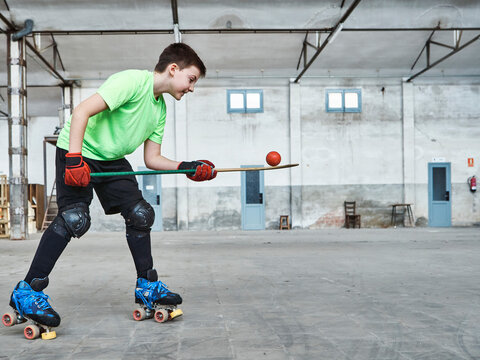 Boy balancing ball on hockey stick during training at court