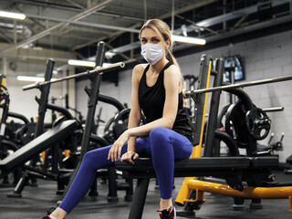 Naklejka na ściany i meble Pandemic gym - woman working out with protective face mask during coronavirus outbreak