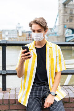 Man wearing face mask while using mobile phone in city during coronavirus outbreak