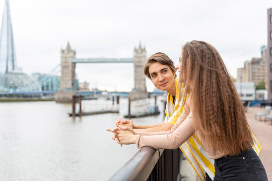 Smiling boyfriend and girlfriend leaning on railing in city, London, UK