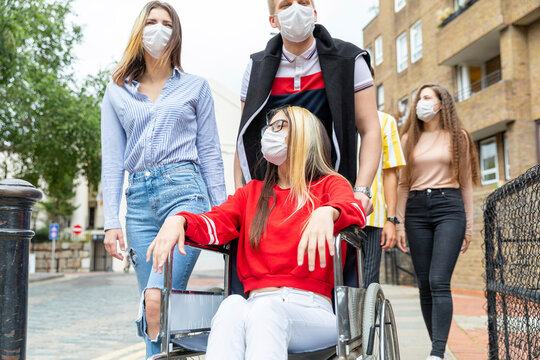 Men and women with disabled female friend wearing masks in city