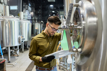 Man working in craft brewery checking clipboard