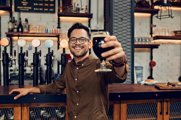 Portrait of a smiling man raising his beer glass in a pub