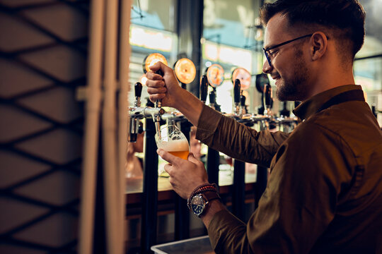 Smiling barkeeper tapping beer in a pub