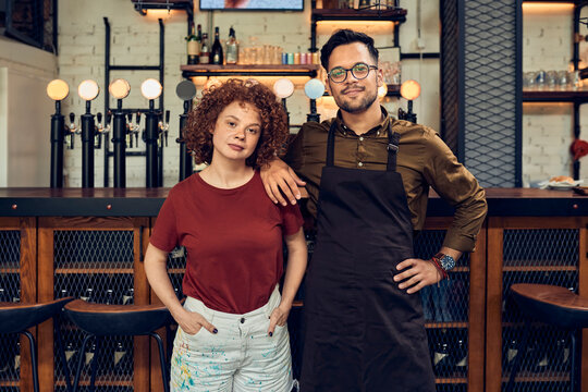 Portrait of confident owner couple at the counter in a pub