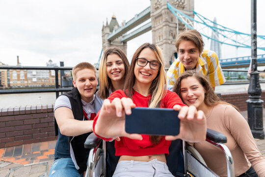 Happy young women and men taking selfie with Tower Bridge in background, London, UK