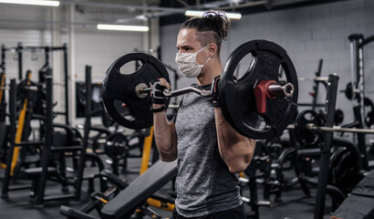 Pandemic gym - man working out with protective face mask during coronavirus outbreak