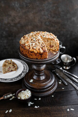 Apple pie decorated with almond flakes on a wooden high stand. Still life with autumn pastries on a wooden table.