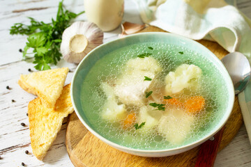 Healthy food concept. Diet turkey soup with vegetables served croutons on a white wooden table.