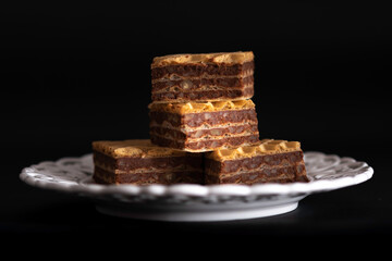 pile of wafers with chocolate on a white plate and a black background